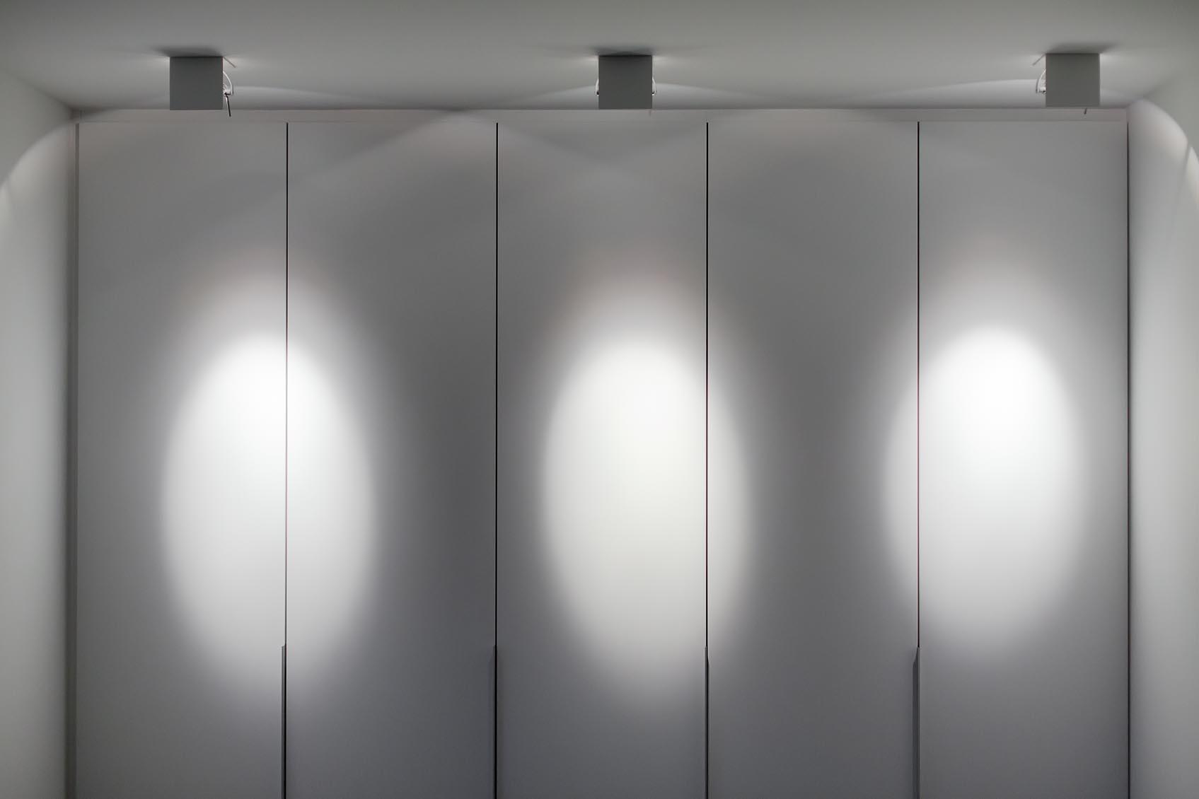 omikron kulturkampf, witte design spot als accentverlichting aan kastenwand