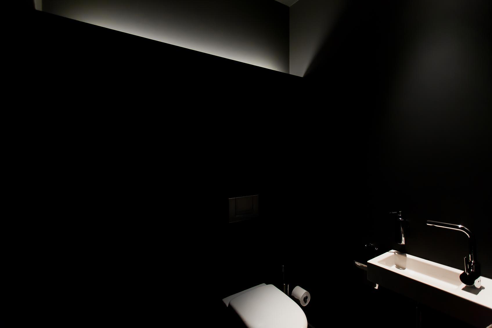 Maatwerk indirecte led verlichting in zwarte ruimte en accenten op witte wc en lavabo